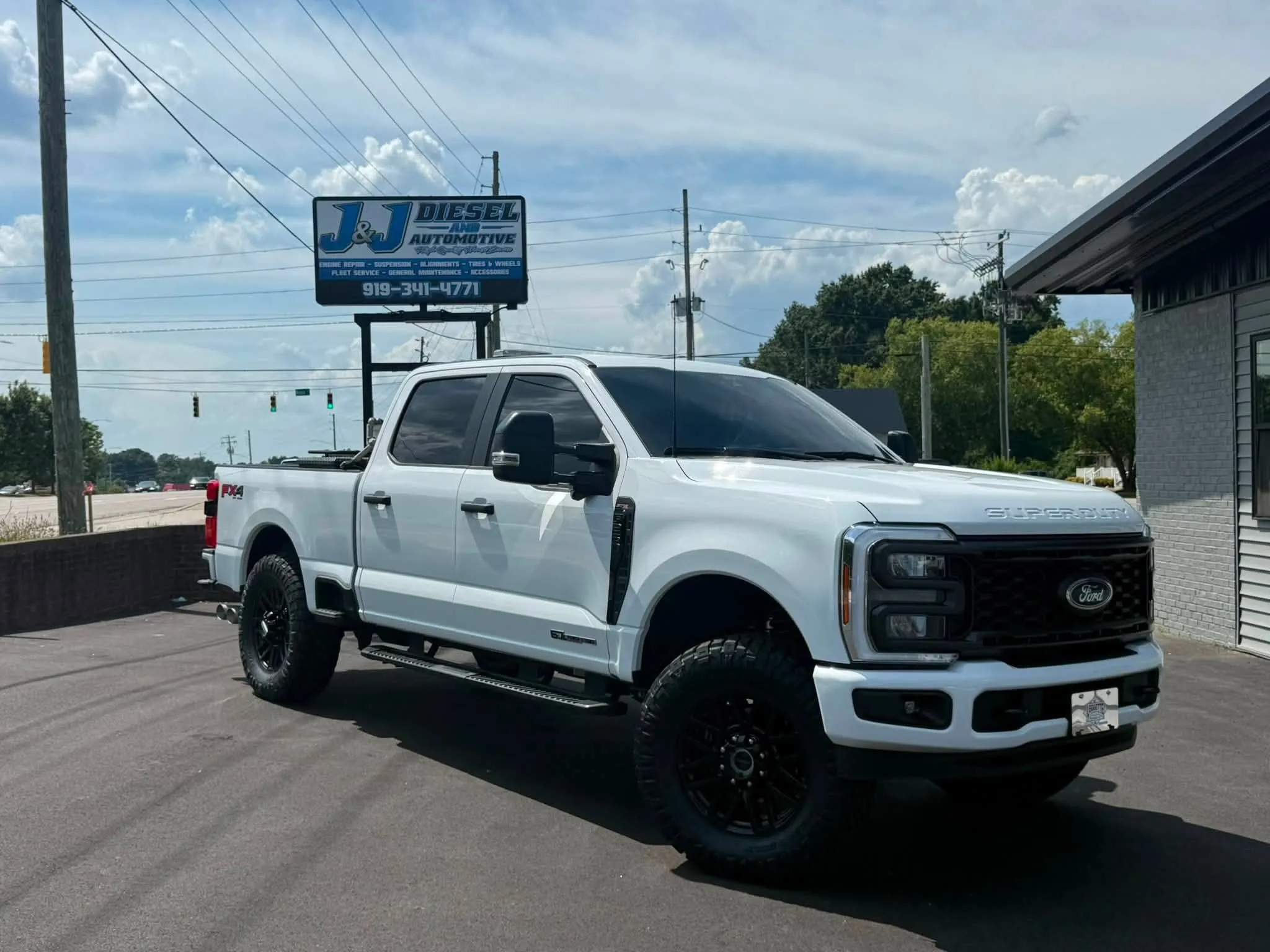 A lifted diesel truck parked in front of the J&J Diesel and Automotive sign in Sanford, NC