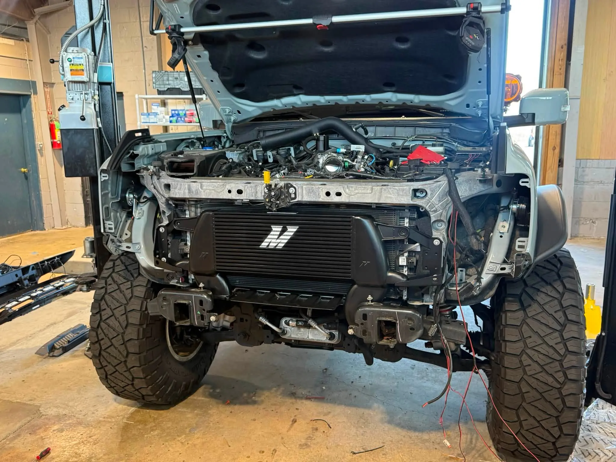 A diesel truck with its front end apart on the lift, mid-build in the J&J shop